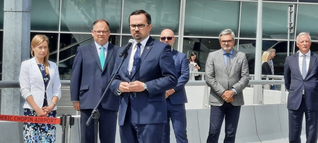 Marcin Horała przemawia na konferencji prasowej przed terminalem na Lotnisku Chopina